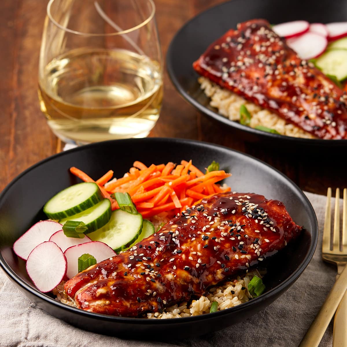 teriyaki salmon bowls in a black bowl served with white wine.