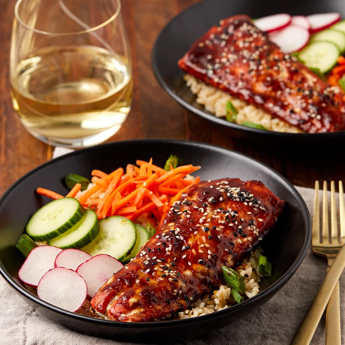 teriyaki salmon bowls in a black bowl served with white wine.