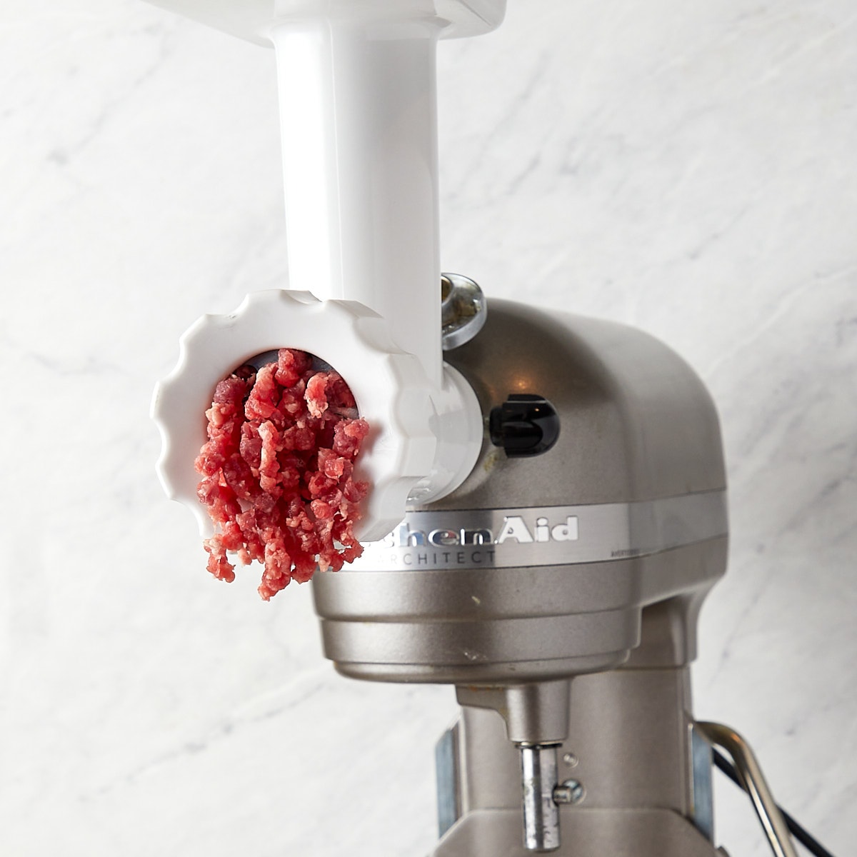 beef being ground in a kitchen-aid food process with a grinder attachment.