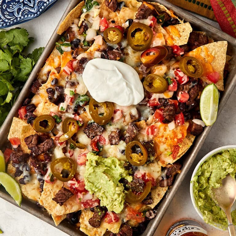 cooked carne asada nachos topped with sour cream and guacamole.