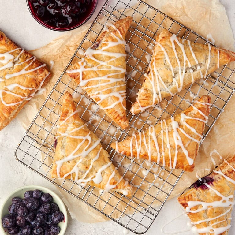 blueberry turnovers with a powder sugar glaze cooling on a wire rack.