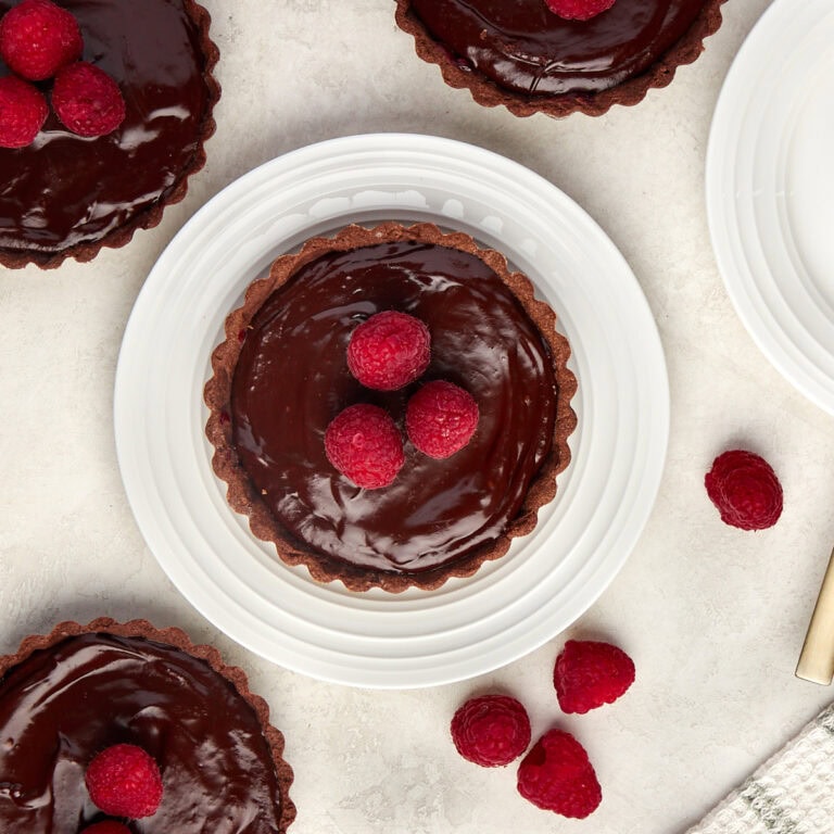 A plate topped with chocolate tart with raspberries.