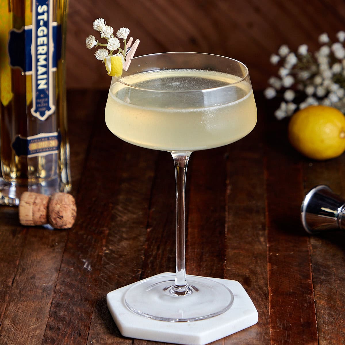 elderflower French 75 in a coup glass garnished with lemon twist and flowers.