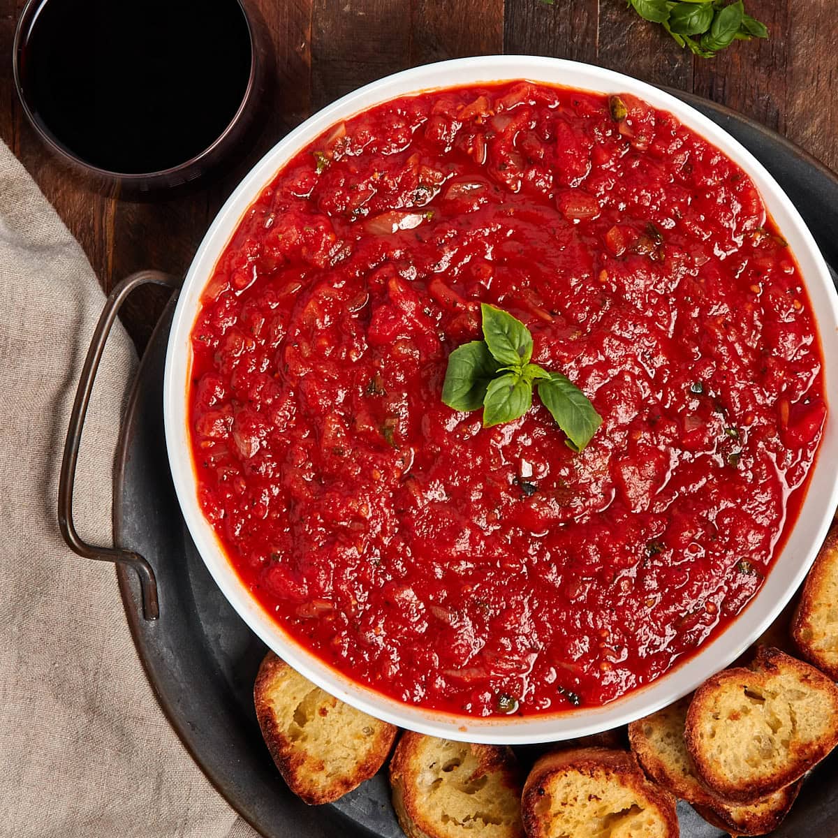 a bowl of marinara sauce with slices of garlic bread on the side.