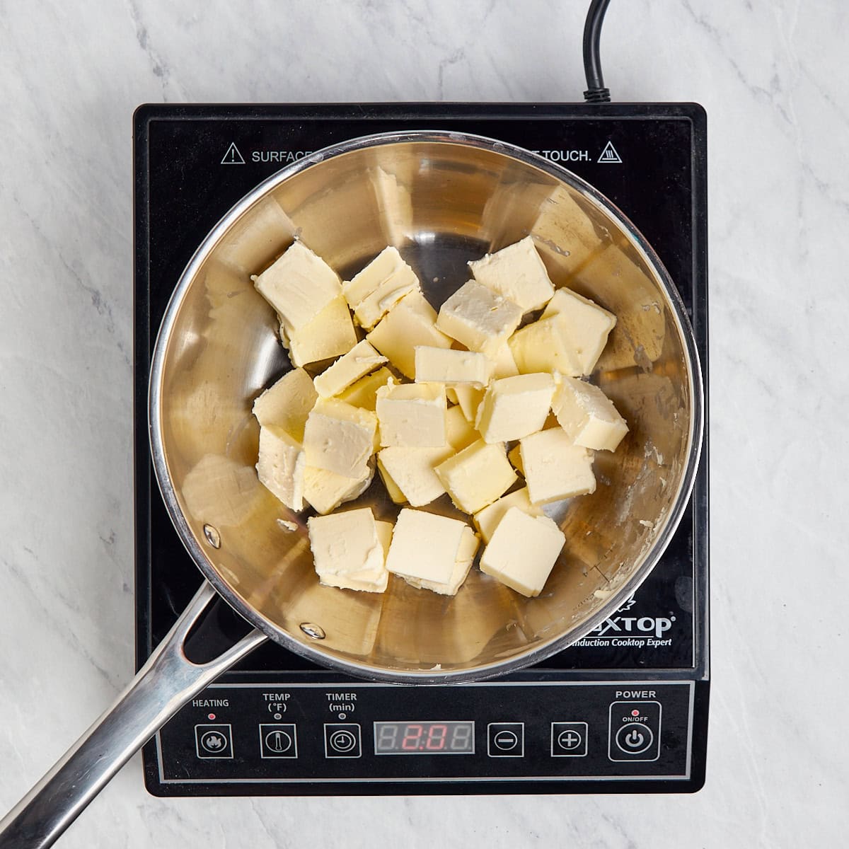 butter cut that has been cut into 1 tablespoon slices sitting in a metal saucepan.