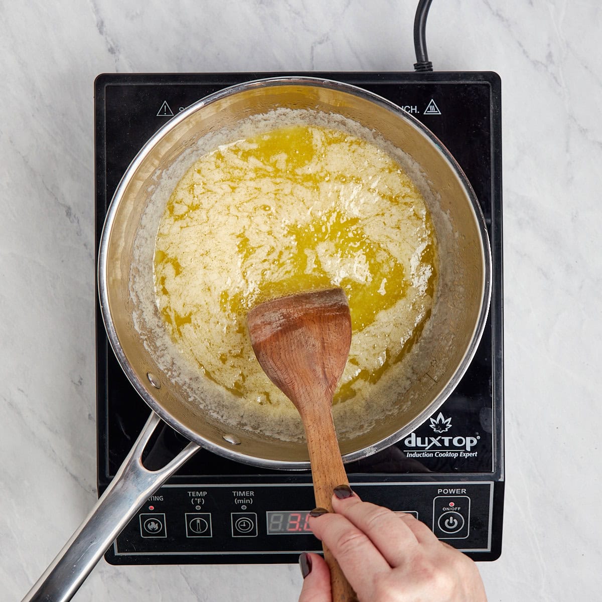 simmering melted butter in a metal saucepan being stirred.