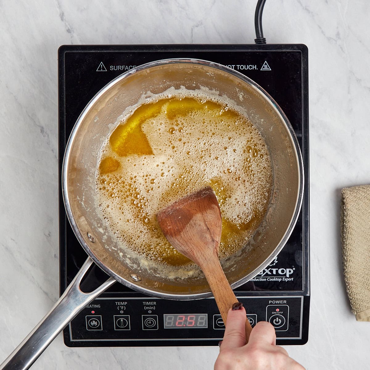 brown butter in a metal saucepan being stirred as it cooks.