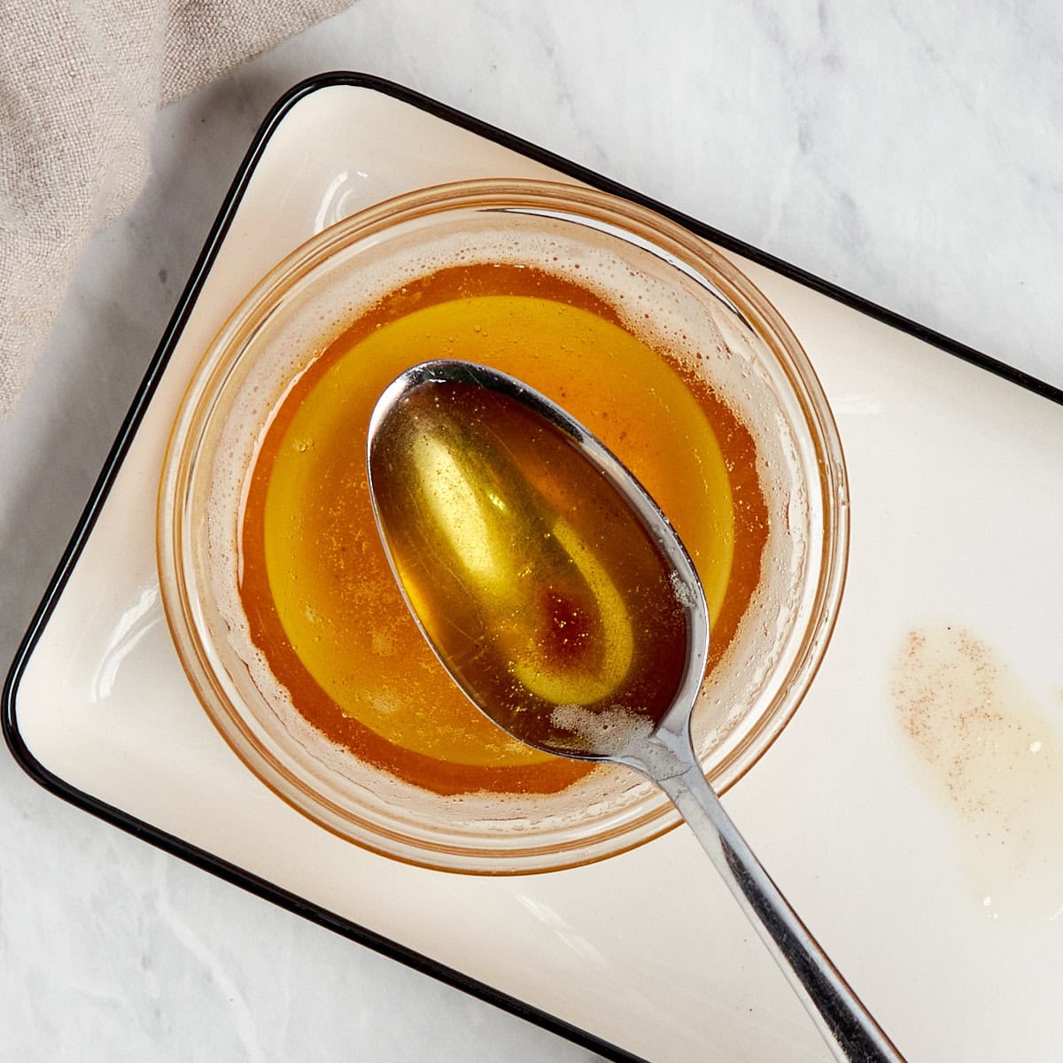 a spoonful of brown butter over a clear bowl.