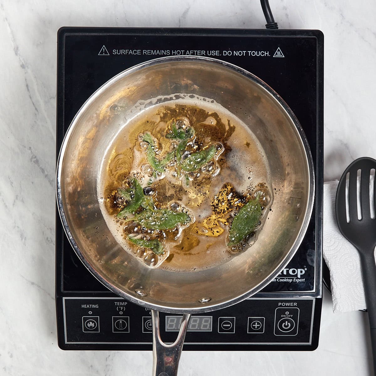 sage frying in brown butter in a sauce pan.