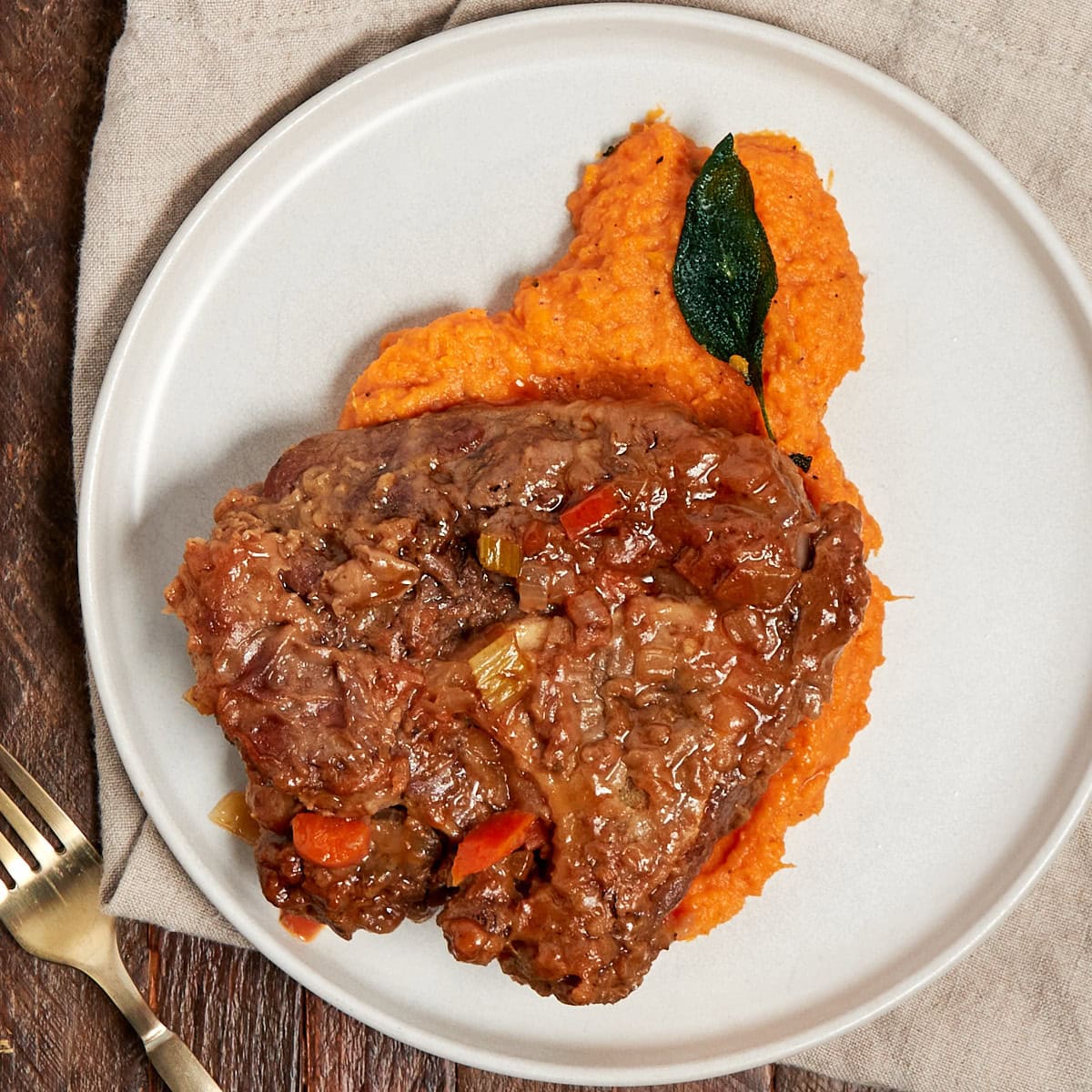 a serving of whipped sweet potatoes on a plate with beef osso buco.