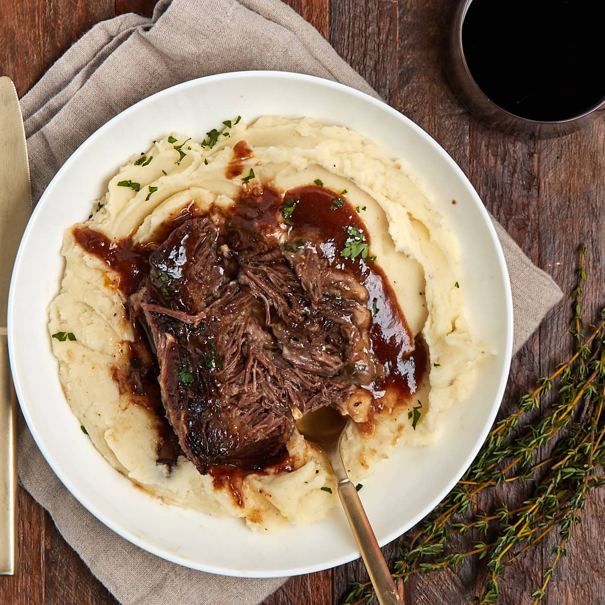 shredded braised short rib with mashed potatoes and gravy in a white bowl.