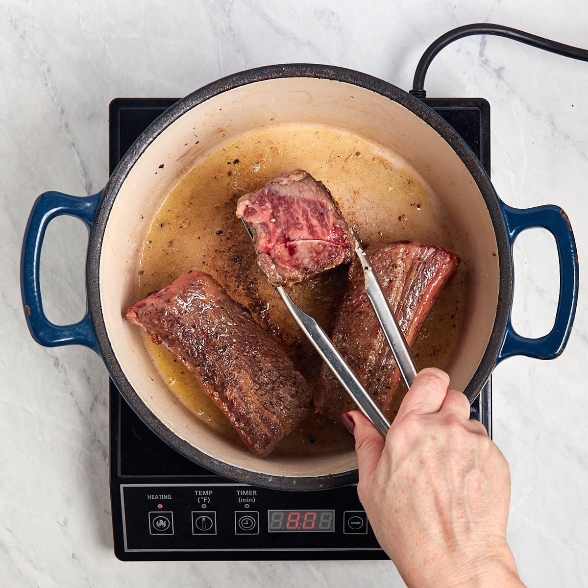 short ribs being browned in a Dutch oven.