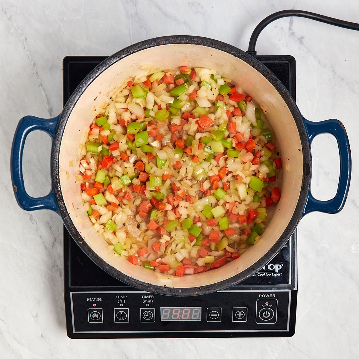 carrots, celery, and onions sautéing in a Dutch oven.