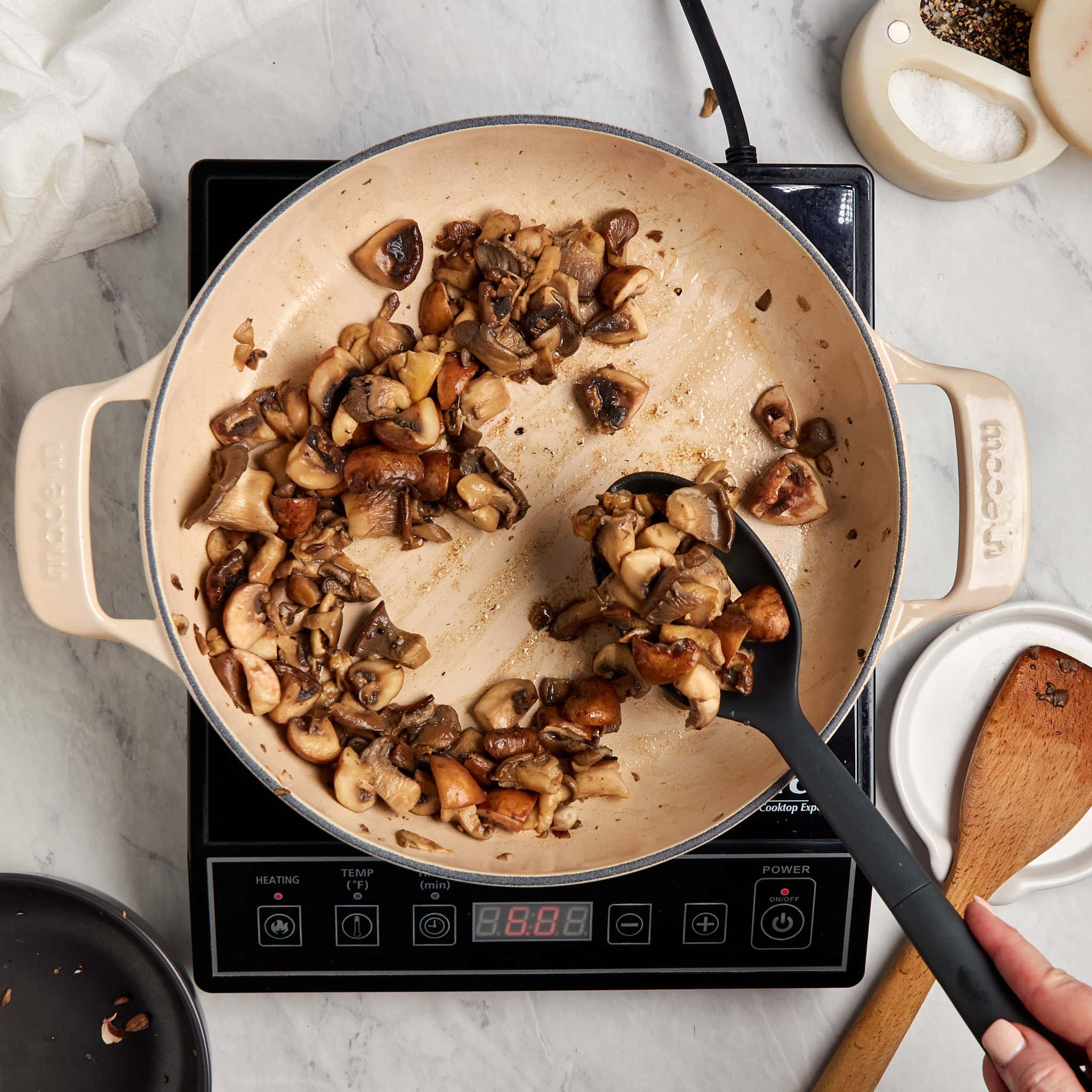 mushrooms being removed from a braiser with a slotted spoon.