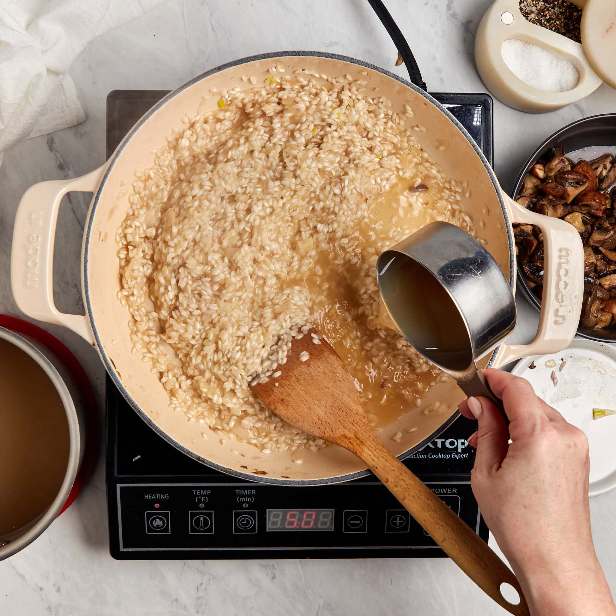 chicken stock being added to the braiser with the rice.