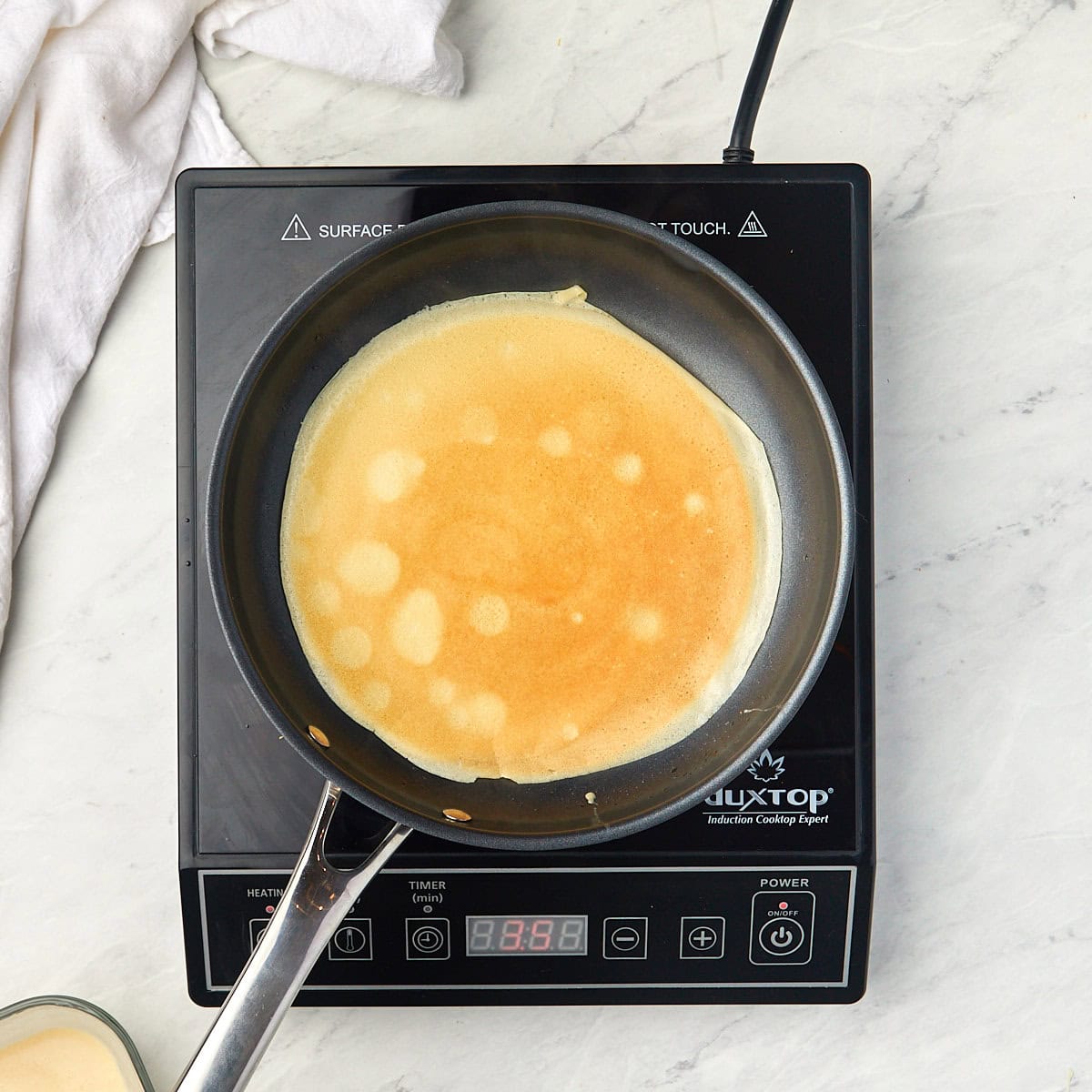second side of crepe cooking in a nonstick skillet.