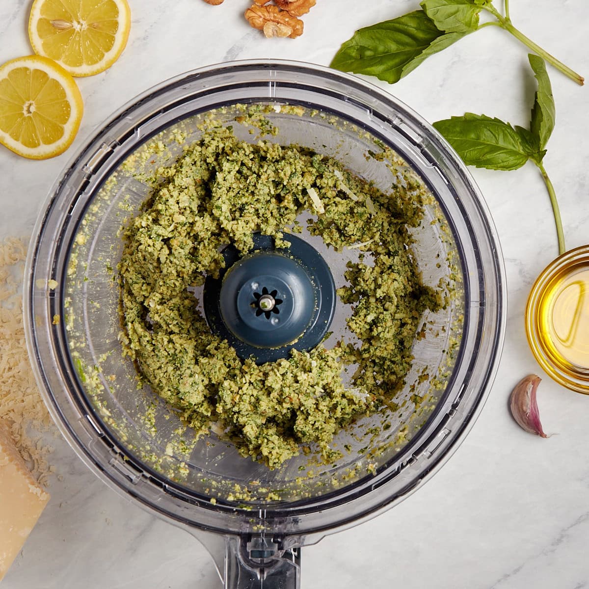cheese added to food processor with basil, walnuts, and garlic.
