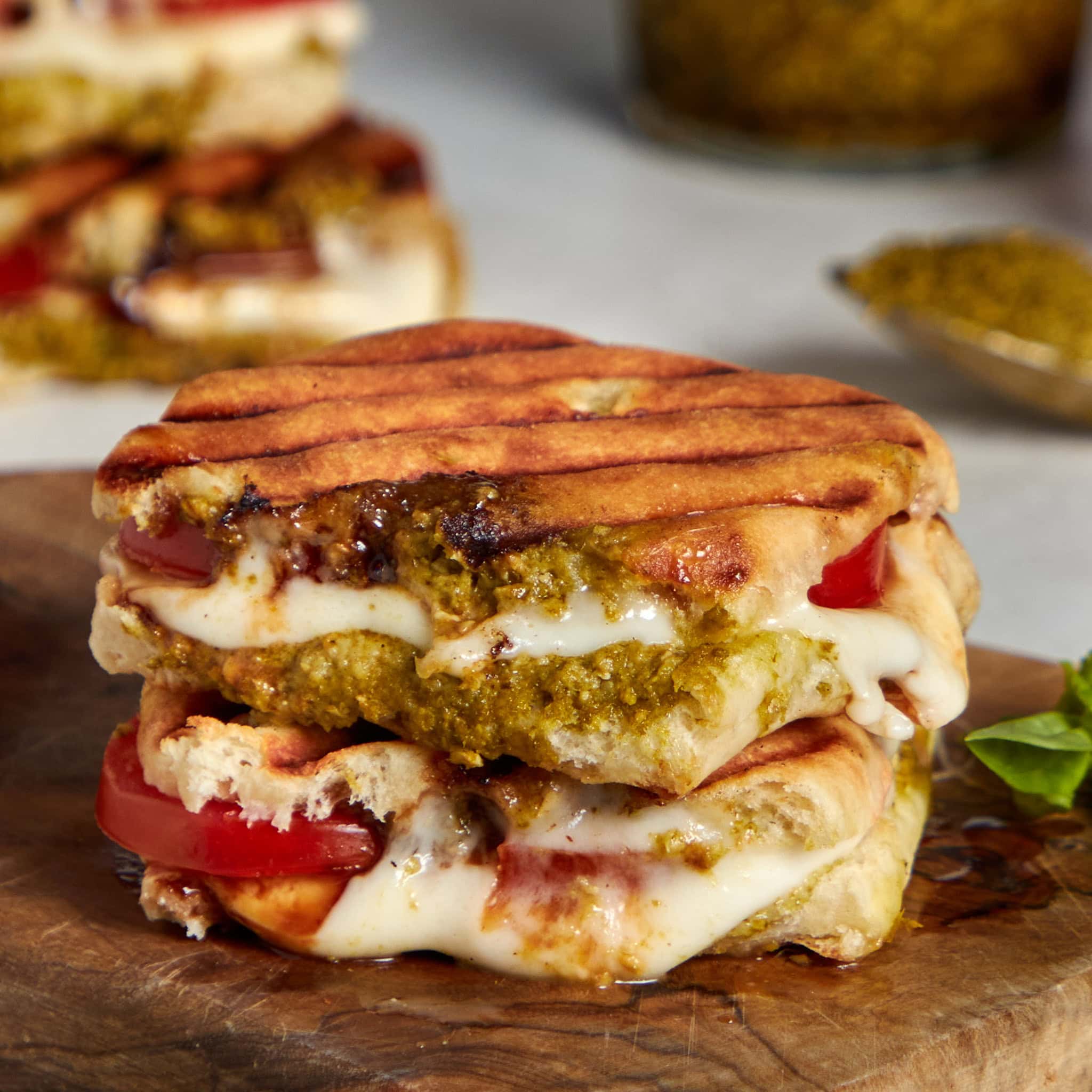 caprese panini stacked on a wood board.