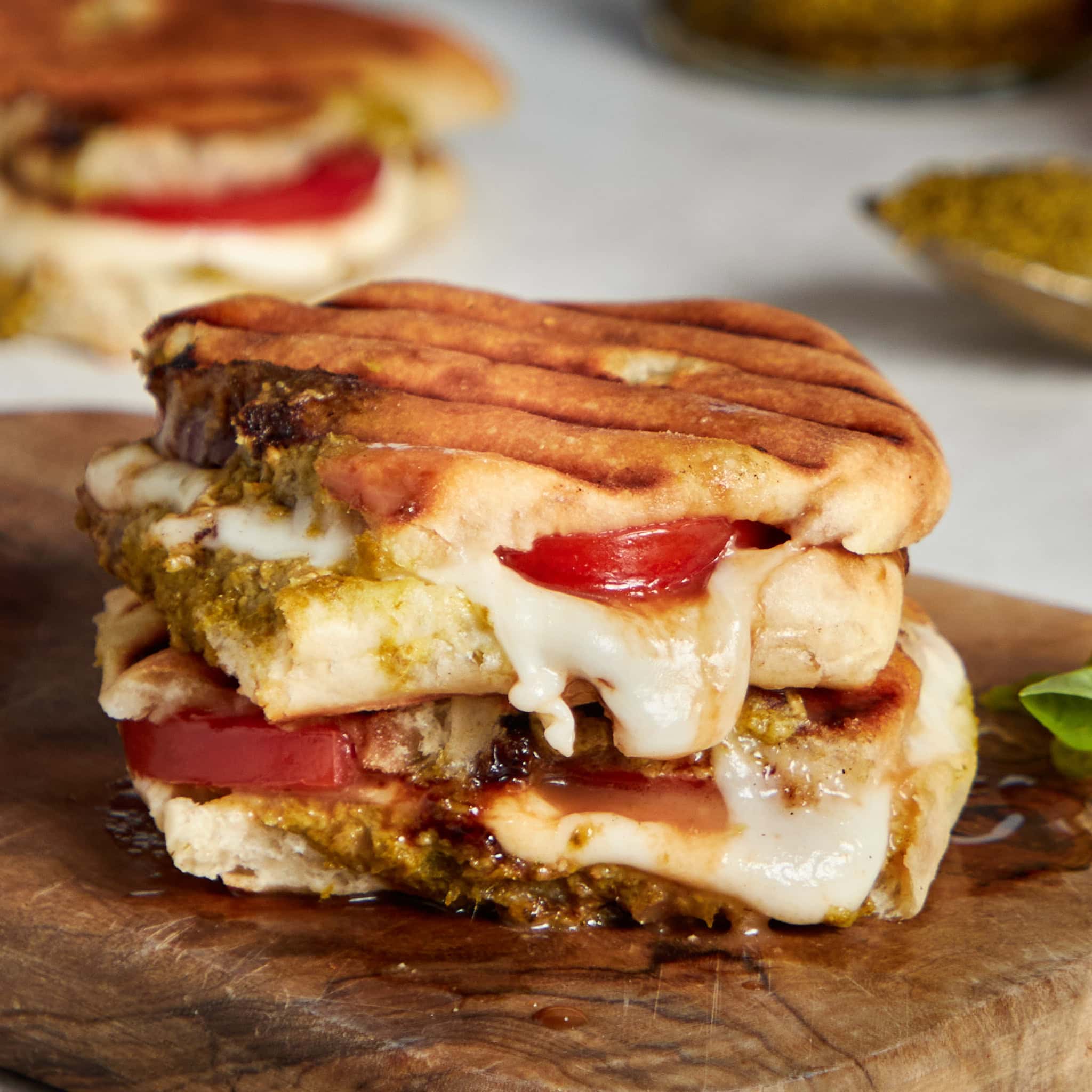 caprese panini stacked on a wood board.