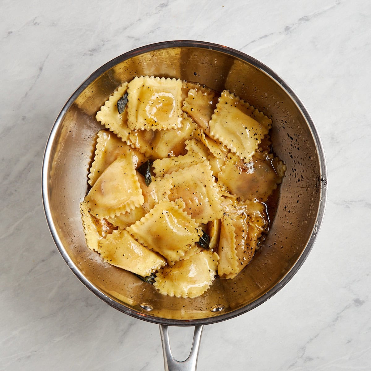 ravioli and sage brown butter in a sauce pan.