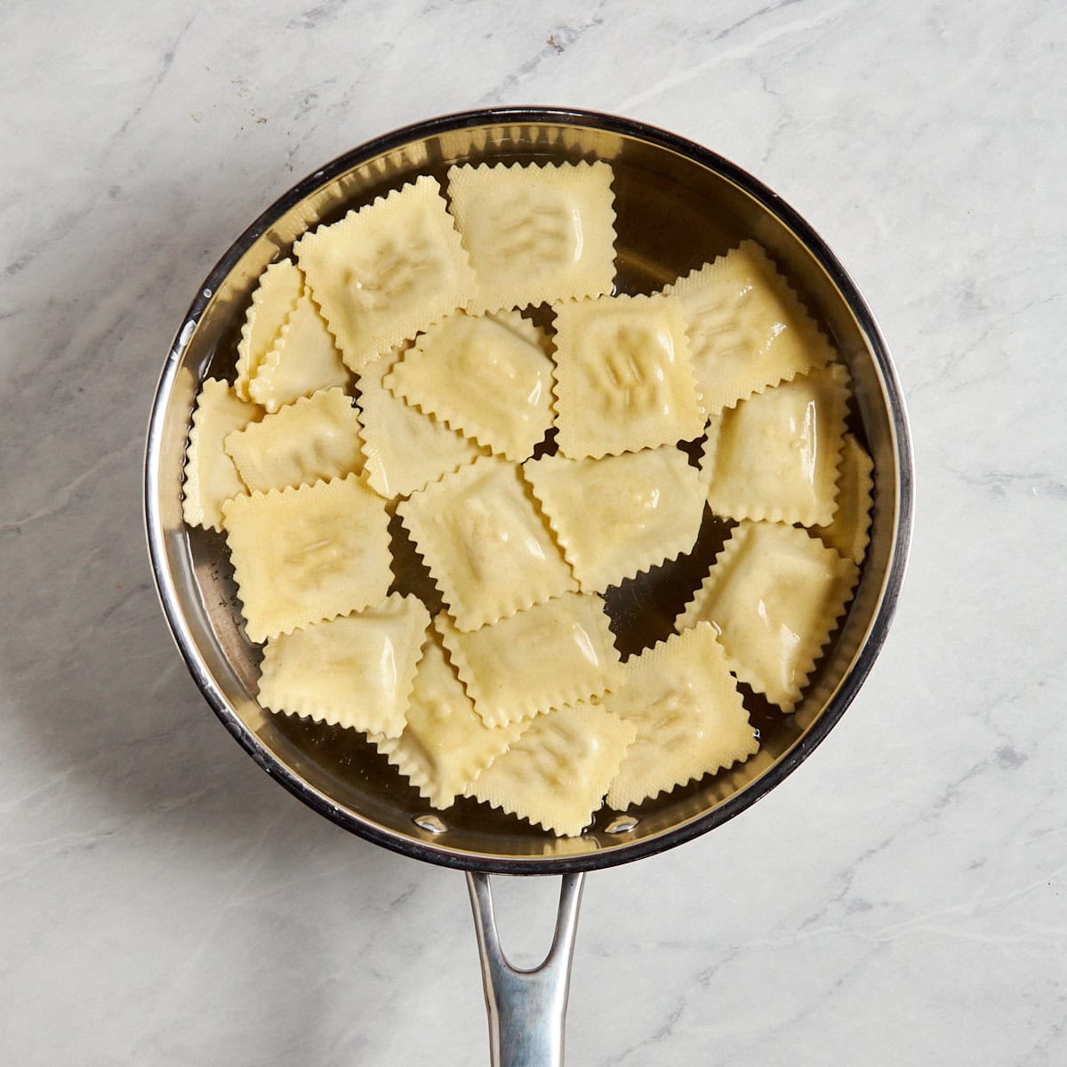 ravioli cooking in water in a sauce pan.