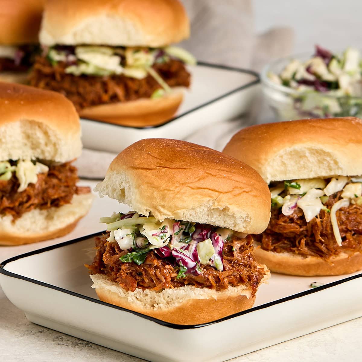 four pulled pork sliders topped with coleslaw.