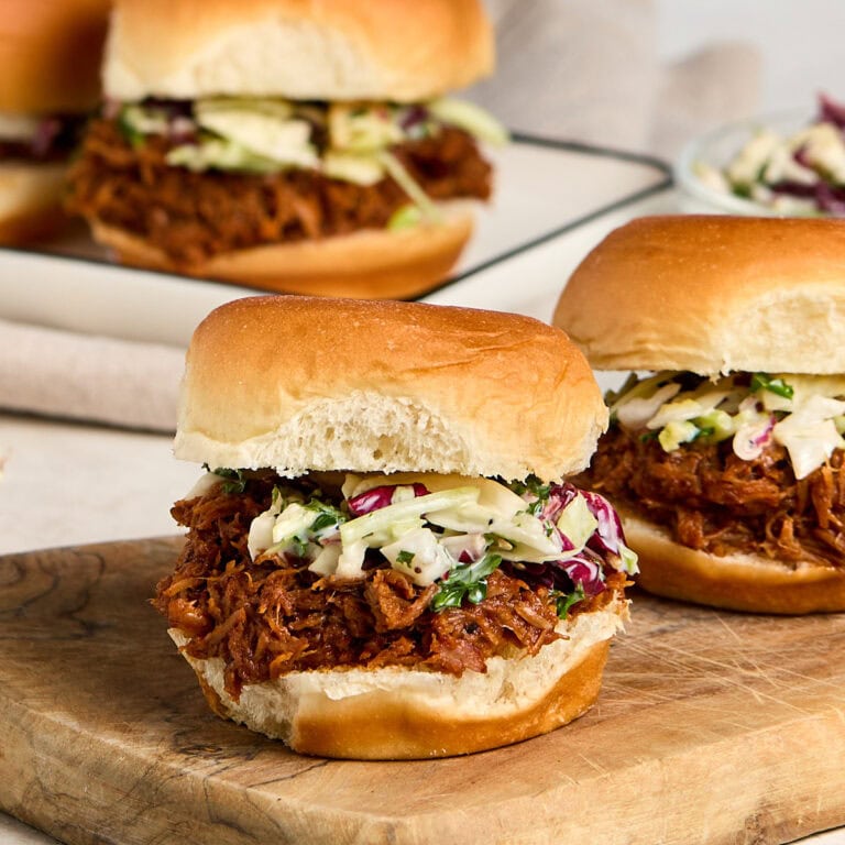 three pulled pork sliders topped with coleslaw.