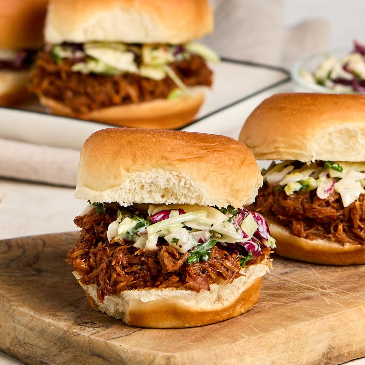 three pulled pork sliders topped with coleslaw.