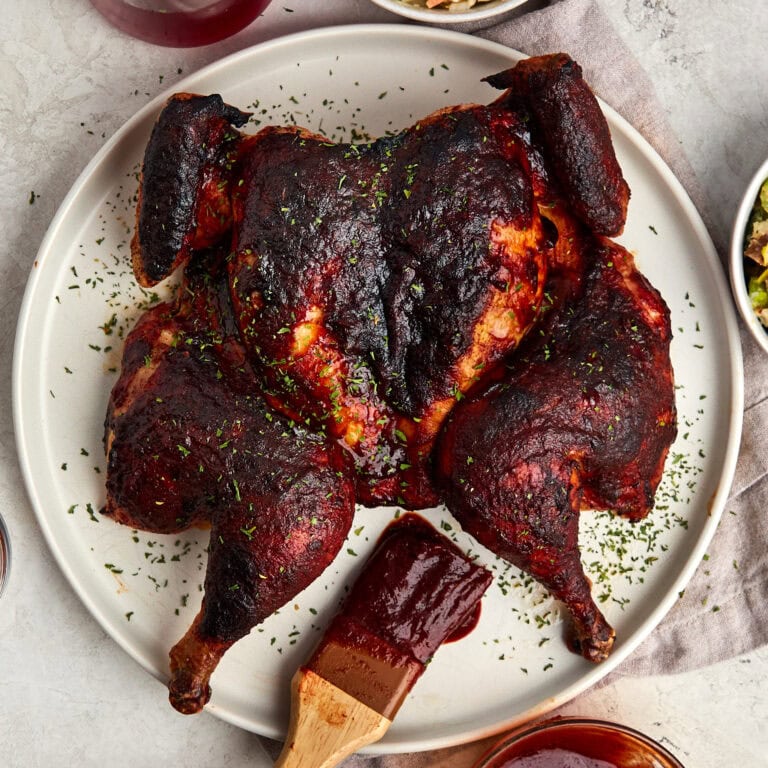 cooked spatchcock chicken on a white plate.