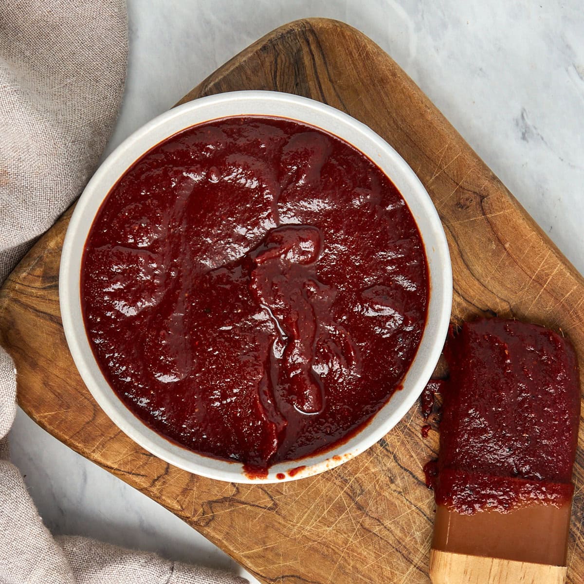 bbq sauce in a white bowl on a wood board.