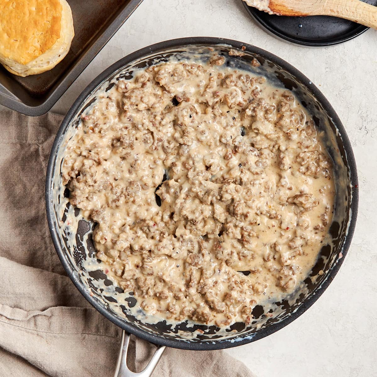 skillet with sausage gravy and biscuits sitting on the side.