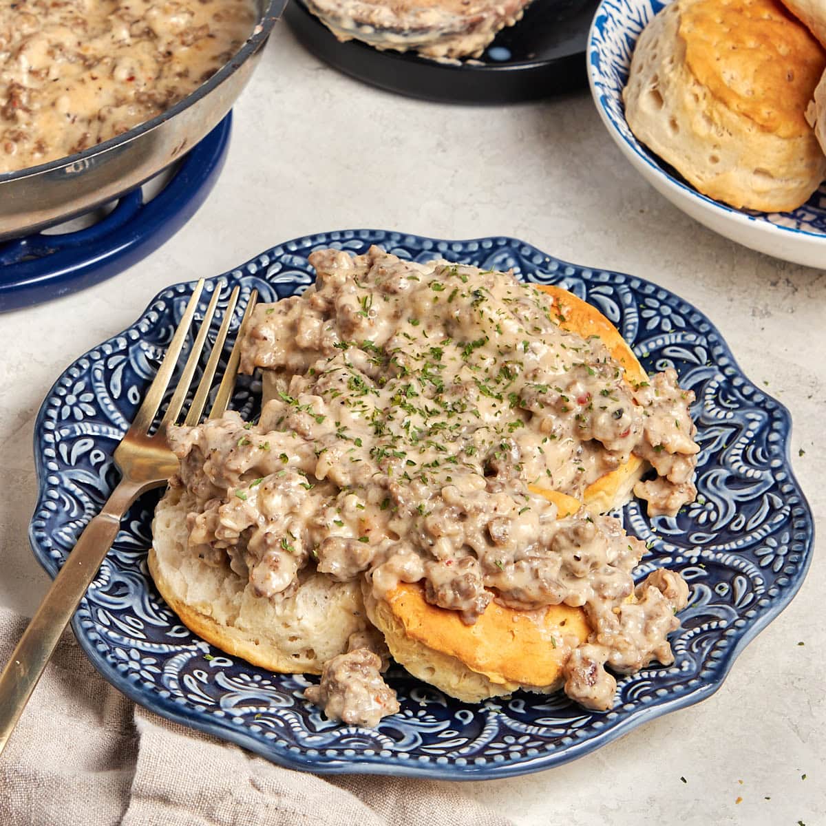 biscuits covered in sausage gravy on a blue plate.