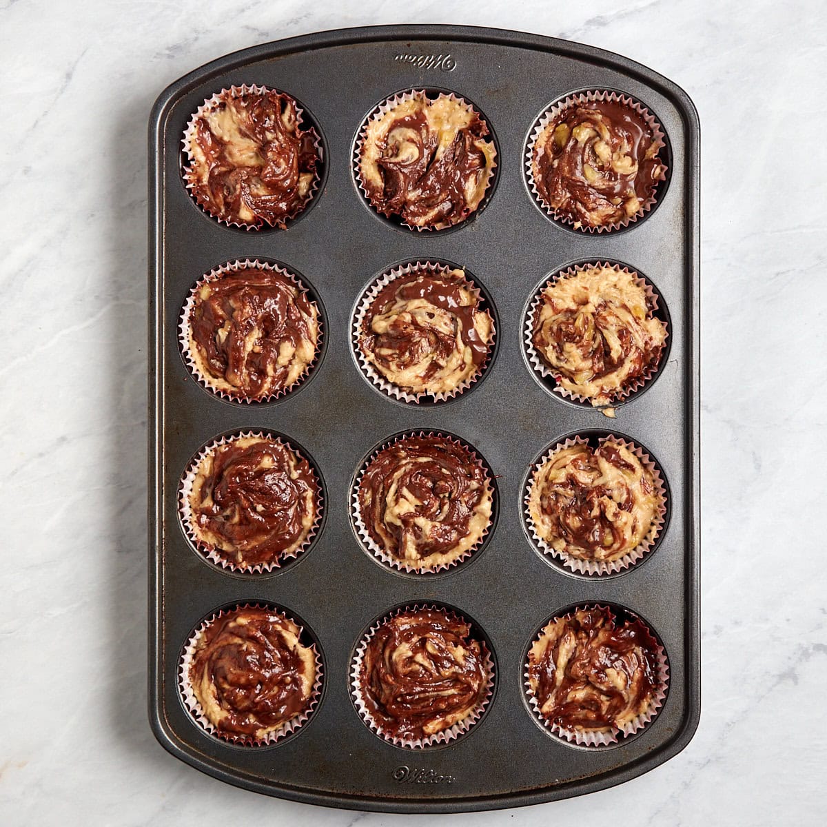 unbaked banana mix with nutella in a muffin tin.