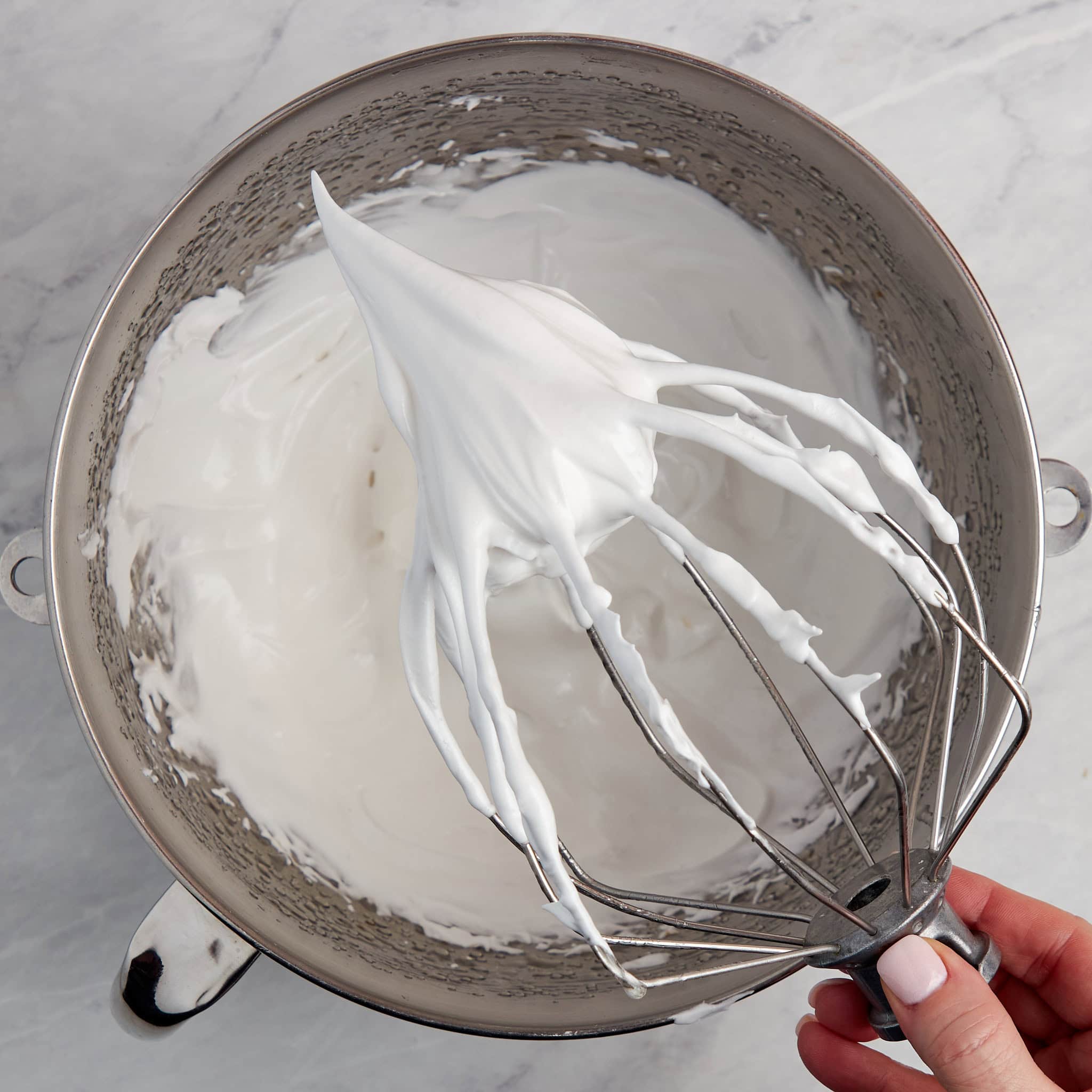 italian meringue in a bowl with a whisk.