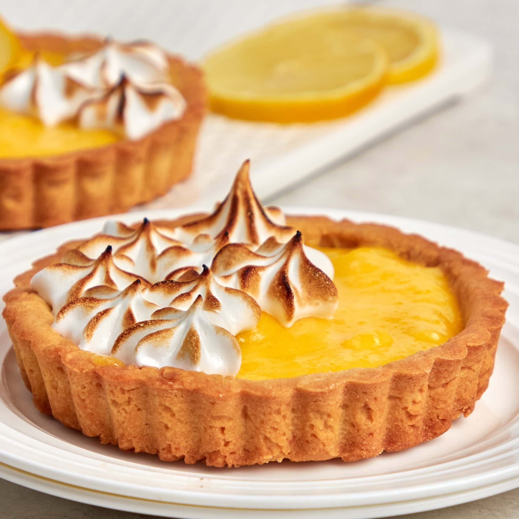a lemon meringue tart garnished with meringue on a white plate.
