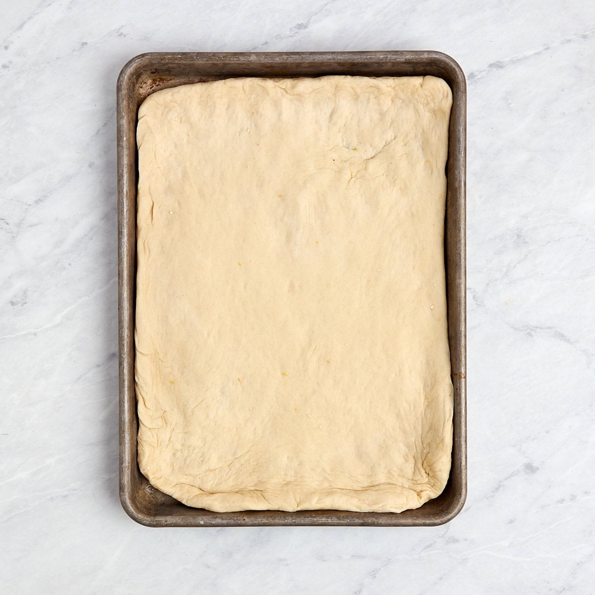 pizza dough stretched out in a baking pan.