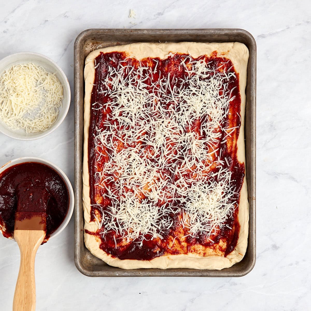 BBQ sauce and cheese on top of stretched pizza dough.