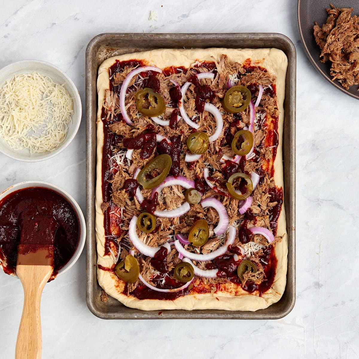 ingredients on top of stretched pizza dough in a sheet pan.