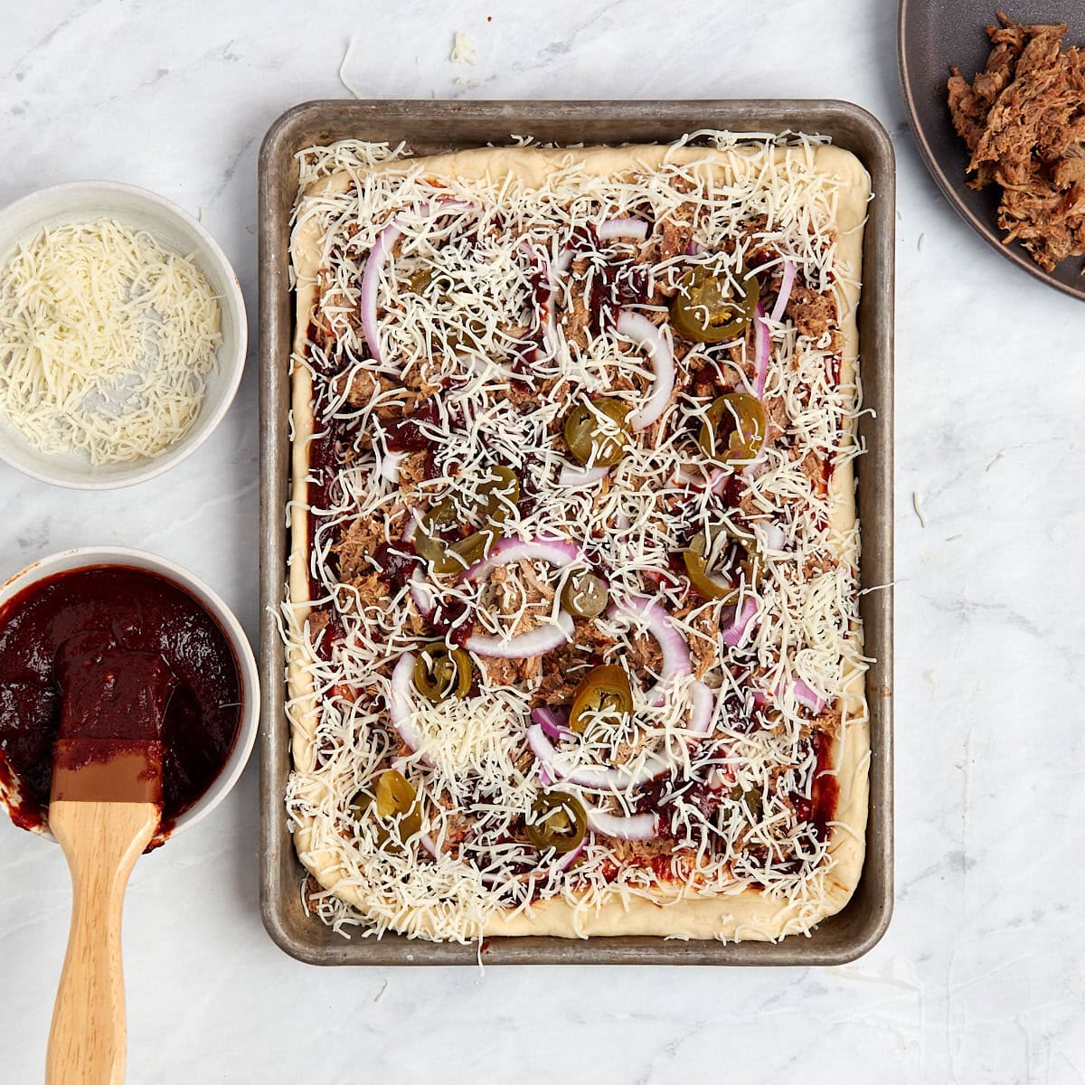 unbaked pulled pork pizza in a sheet pan.