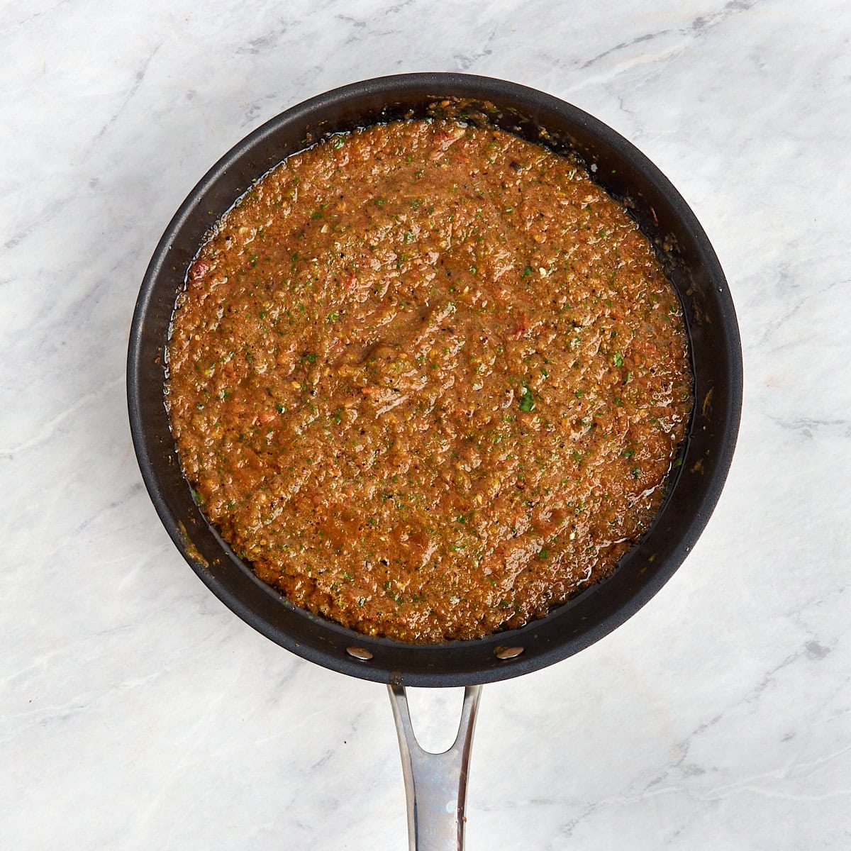 salsa roja being cooked in a skillet with olive oil.