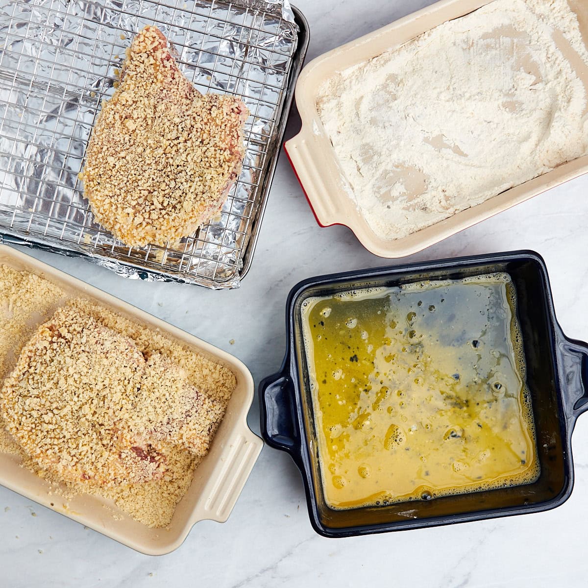 pork chop being dipped into panko bread crumbs.