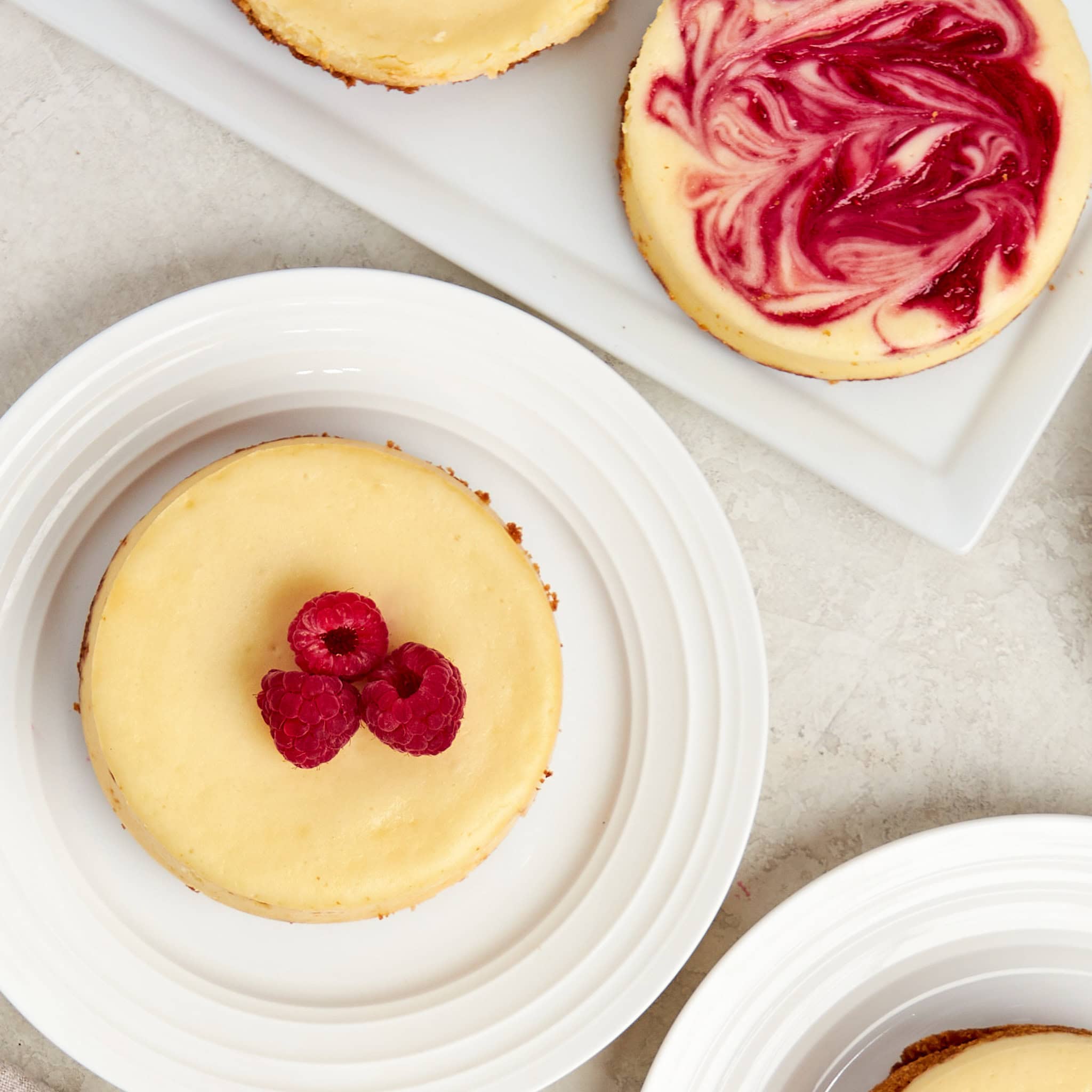 individual cheesecake topped with raspberries on a white plate.