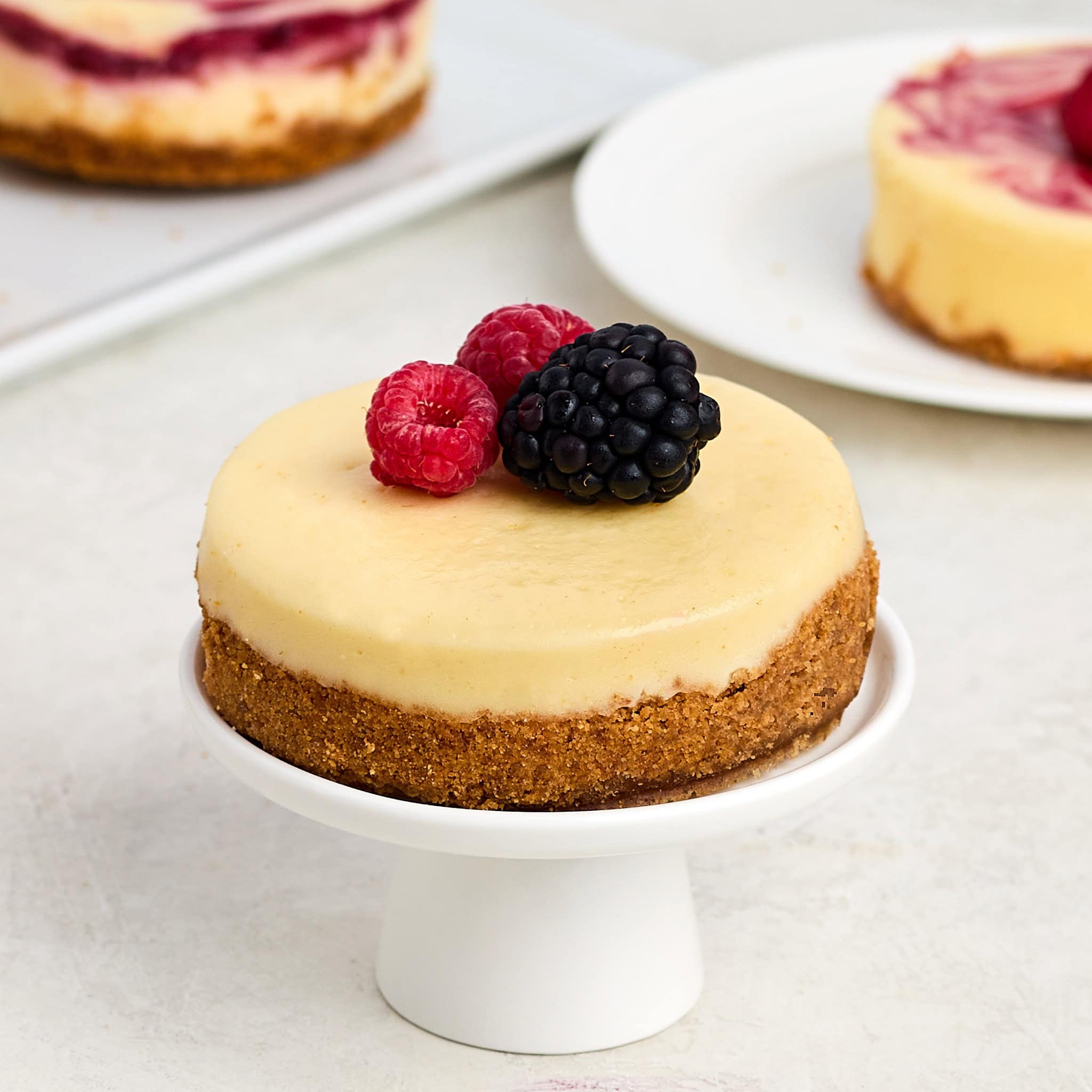 individual cheesecake topped with berries on a cupcake stand.