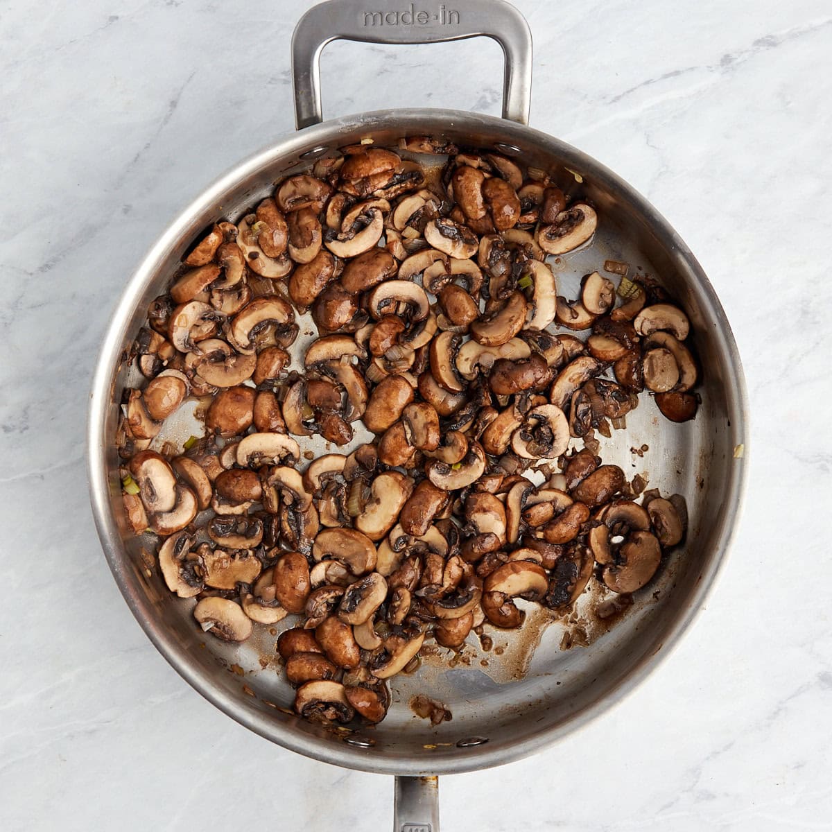 mushrooms cooked down in a large skillet.