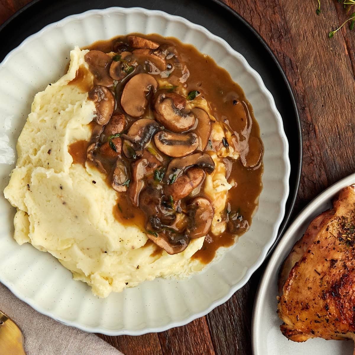 mushroom onion gravy served over southern-style mashed potatoes with a piece of chicken.
