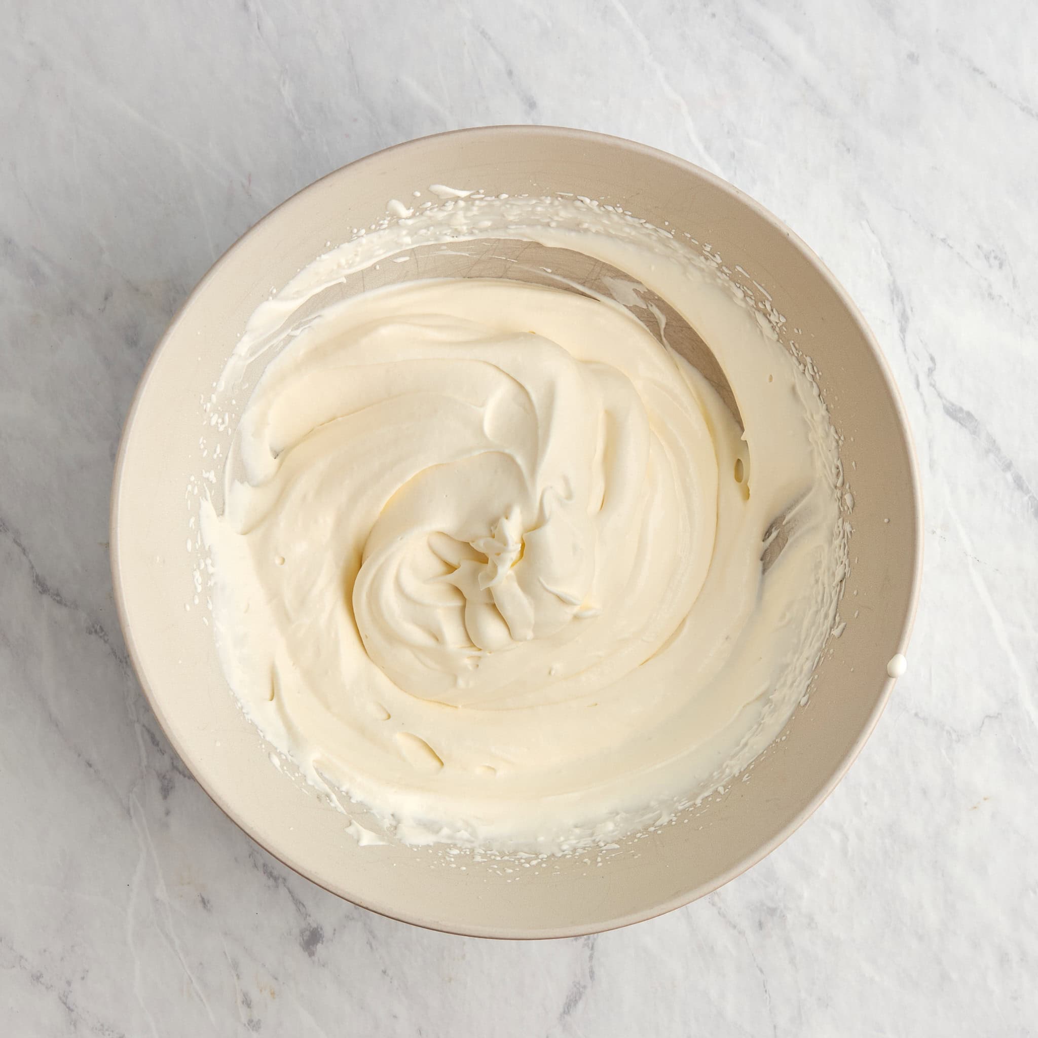 heavy whipping cream whipped to soft peaks in a mixing bowl.