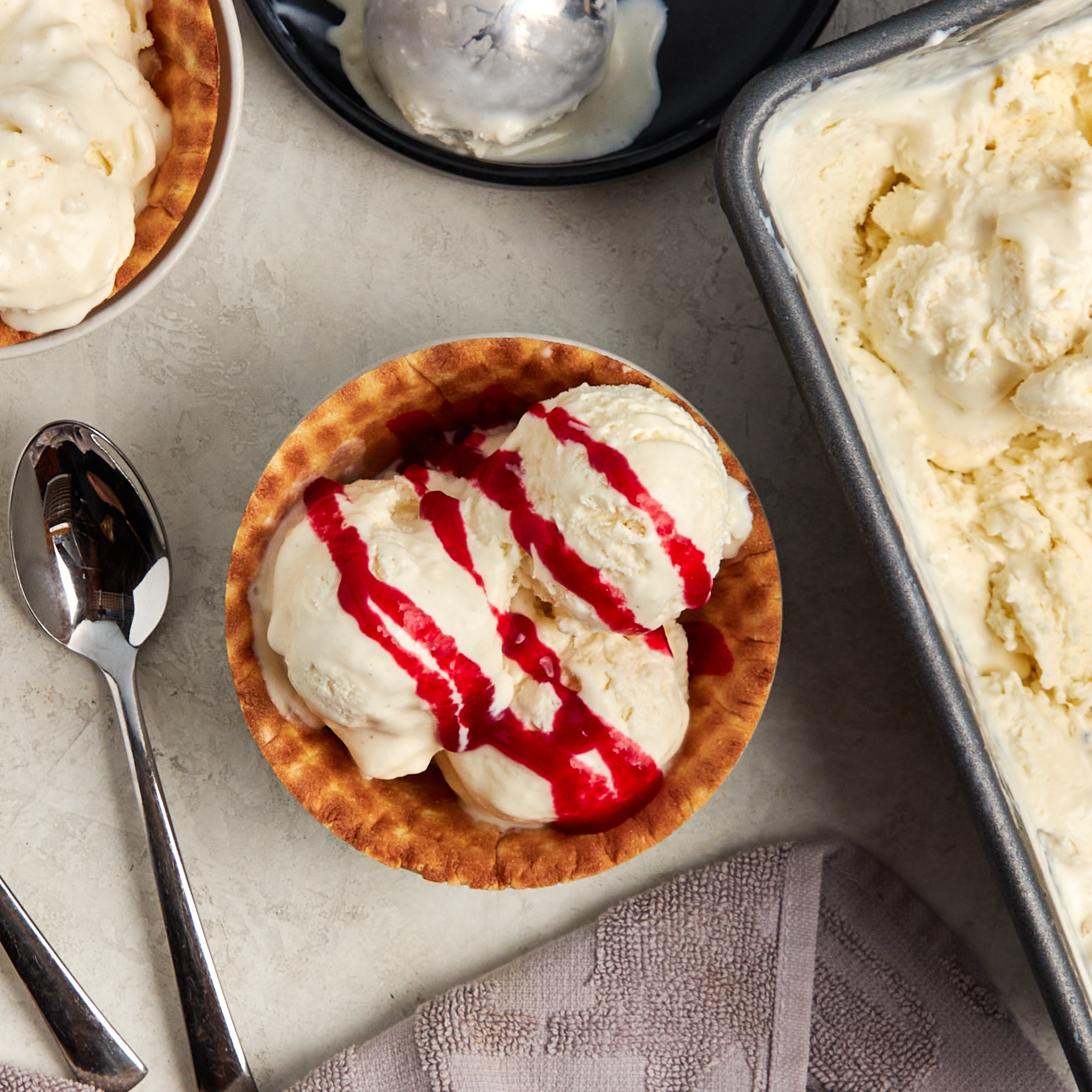 vanilla ice cream in a waffle bowl drizzled with raspberry syrup.