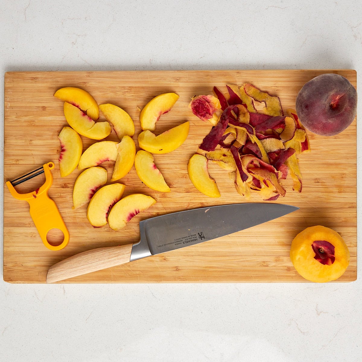 peaches peeled and cut on a wood cutting board.