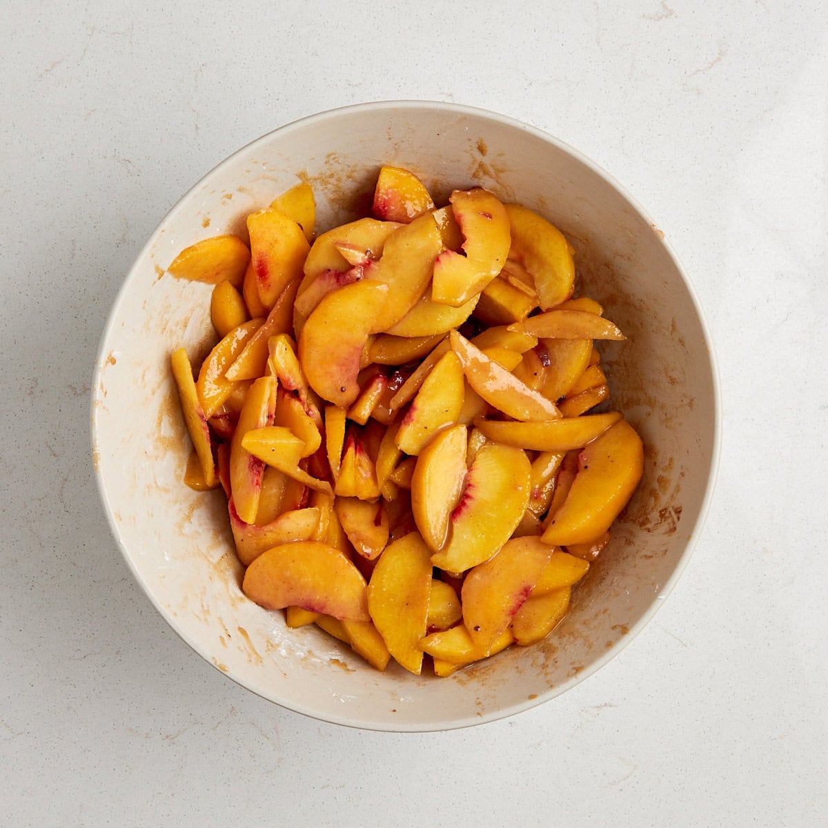 cut peaches tossed in the other ingredients in a bowl.