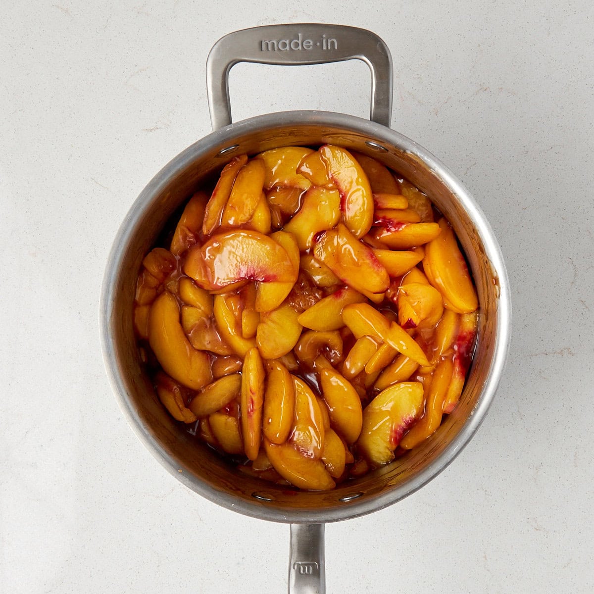 cooked peaches in a sauce pan.
